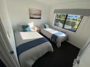 two beds in a small room with a window at Soul Sanctuary, with outdoor bath in Raglan