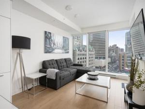 - un salon avec un canapé et une grande fenêtre dans l'établissement Spectacular Skyline Views - Downtown Montreal - Luxury Condo & Penthouse, à Montréal