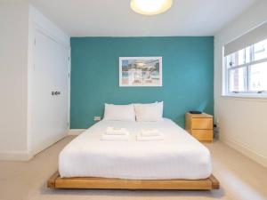 Cette chambre comprend un grand lit blanc et un mur bleu. dans l'établissement Pass the Keys Stylish West End Detached Mews, à Glasgow