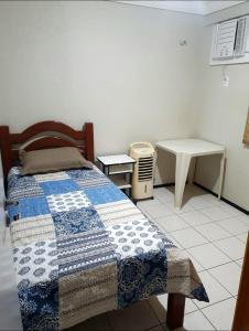 a bedroom with a bed and a table and a desk at Espaço para sentir-se bem. in Fortaleza