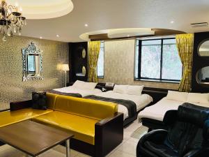 a hotel room with two beds and a yellow couch at Hotel Square FujiGotemba in Gotemba