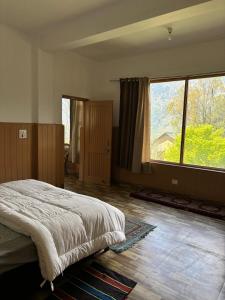 a bedroom with a bed and a large window at Naggar Manali's Paradise at Chanderlok in Nagar
