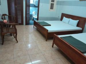 een kamer met 2 bedden en een tafel en een stoel bij An An Hotel in Ho Chi Minh-stad