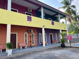 um edifício colorido com bancos em frente em OYO 90967 Homestay Chalet Warisan Siti em Kampung Padang Masirat