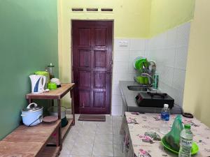 cocina con puerta marrón y fregadero en OYO 90967 Homestay Chalet Warisan Siti en Kampung Padang Masirat