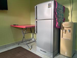 a refrigerator in a kitchen with a table and a stool at OYO 90967 Homestay Chalet Warisan Siti in Kampung Padang Masirat