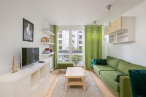 a living room with a green couch and a tv at Ecru Apartment near Norblin Factory WWA76 in Warsaw