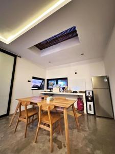 eine Küche mit einem Holztisch und einem Kühlschrank in der Unterkunft Brand New Two-Bedroom Villa with rice field views. in Tanah Lot