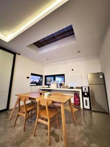 a kitchen with a wooden table and a refrigerator at Brand New Two-Bedroom Villa with rice field views. in Tanah Lot