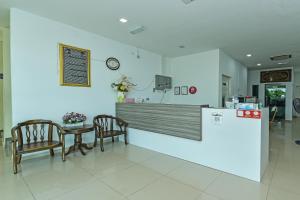 a waiting room with a table and chairs and a counter at OYO 275 Senyum Inn in Pantai Cenang