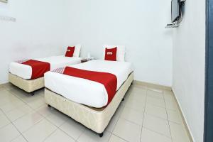 OYO 275 Senyum Inn في بانتايْ سينانج: سريرين مع شراشف حمراء وبيضاء في الغرفة