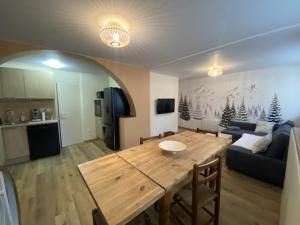 cocina y sala de estar con mesa de madera en Les balcons de l'Arbizon, en Guchen
