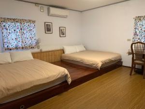 Un dormitorio con 2 camas y una silla. en Shitaoyuan, en Sanyi