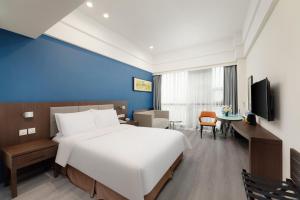a bedroom with a large white bed and a blue wall at Holiday Inn Express Chengdu Wuhou by IHG-Wuhou Temple and Jinli in Chengdu