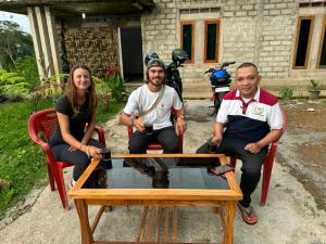 um grupo de três pessoas sentadas à volta de uma mesa em Wisma PO'ONG em Ruteng