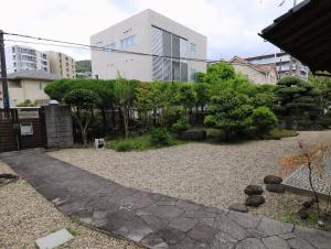 een tuin met rotsen en bomen en een gebouw bij Shionome house in Ikuma