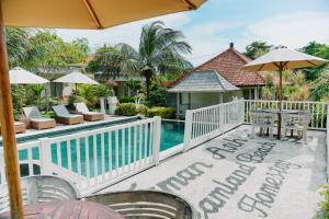 un complejo con piscina con mesa y sombrilla en Taman Asih Bingin Homestay, en Uluwatu 10 fotos más