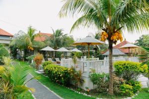 a garden with a white fence and a palm tree at Taman Asih Bingin Homestay in Uluwatu