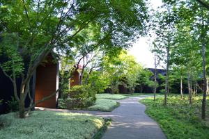 einen Weg durch einen Garten mit Bäumen und einem Haus in der Unterkunft 御宿 白金の森 in Kikuchi