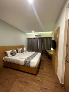 a bedroom with a bed and a desk and a television at Hotel Indriya Wayanad in Kalpetta