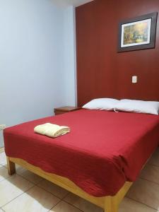 a bed with a red blanket and two towels on it at Isabel's INN - Nasca in Nazca