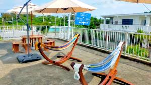 2 Stühle, ein Tisch und ein Regenschirm in der Unterkunft 宮古島 Guesthouse Re-Spect in Miyako-jima