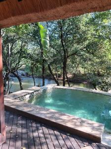 a swimming pool on a deck with trees and water at Dreamy 3 bedroom villa on the edge of the Sabie River in Kruger Park Lodge in Hazyview