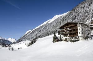 a building on a snow covered slope in front of a mountain at Versalerhof in Ischgl