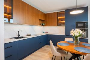 Una cocina con gabinetes azules y una mesa de madera. en Aatrium Kinnisvara Riia str 22 apartment 80 m2 with 45 m2 terrace, en Tartu