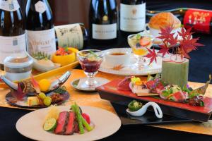 御宿 白金の森 في Kikuchi: طاولة مع أطباق من الطعام وزجاجات من النبيذ