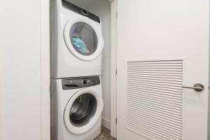 a laundry room with a washer and dryer next to a door at High Rise 3 Bedroom Sleeps 9 Walk to Cripto Arena in 20 Minutes in Los Angeles