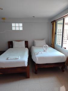 two beds with white towels on them in a room at Thosawan Resort ทศวรรณ รีสอร์ท in Khong Chiam