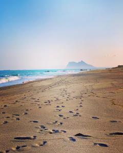 una playa con huellas en la arena y el océano en Casa del Golf, en Alcaidesa