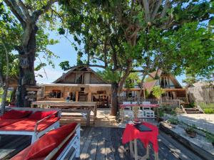 a patio with chairs and a table and a house at Sunset Moyo Bungalows in Moyo Island