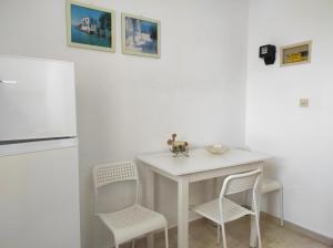 a white kitchen with a white table and chairs at Νέος Πύργος Studio in Neos Pirgos