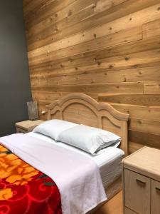 1 dormitorio con 1 cama con pared de madera en Dalat Second Vacation Home, en Lantzville