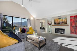 een woonkamer met een bank en een open haard bij Distinctive Stylish and Spacious Family Home in Queenstown