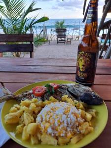 a plate of food on a table with a bottle of beer at Waves cabana kalametiya in Ranna