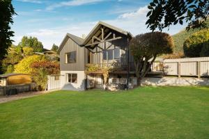 a house with a white fence and a yard at Distinctive Stylish and Spacious Family Home in Queenstown
