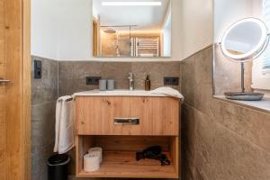 W łazience znajduje się umywalka i lustro. w obiekcie Maurig Appartements w mieście Elbigenalp