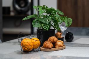 einen Tisch mit einem Korb mit Orangen und Croissants sowie einer Pflanze in der Unterkunft Glamour Apartament - Centrum Poznania in Posen