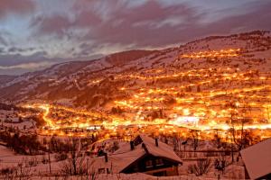 a city lit up in the snow at night at LE GRENIER DES MIOS in La Bresse