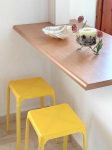 a shelf with two yellow stools and a vase with a candle at Νέος Πύργος Δίκλινο in Néos Pírgos