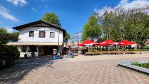 a building with red umbrellas and tables and chairs at Apartament Garncarska in Elblag