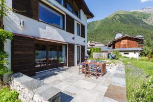 a patio with a table and chairs next to a building at Chalet Plein Centre - Savoyard Moderne - Happy Rentals in Chamonix