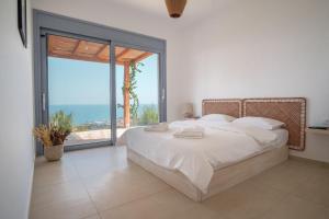 a bedroom with a large bed and a large window at Villa Thea in Mochlos