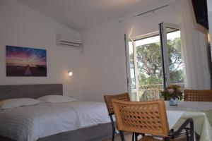 sypialnia z łóżkiem, stołem i oknem w obiekcie Apartments Popo w mieście Starigrad-Paklenica