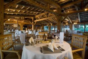 a dining room with white tables and chairs and wooden ceilings at LANIG Hotel Resort&Spa - Wellness und Feinschmeckerhotel - family owned and managed in Oberjoch