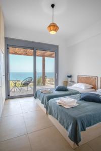 a bedroom with two beds and a view of the ocean at Villa Thea in Mochlos