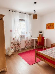 a bedroom with a table and a red chair at Ferienhaus Ebern-Sölln in Ebern